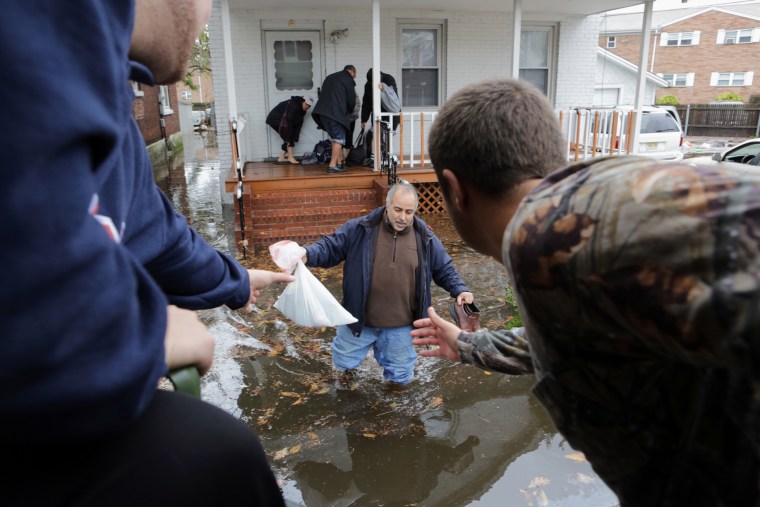 Miatid Amini makes his way with his family onto a truck in Moonachie, N.J., on Tuesday. Frank Mercadante, right, assists.