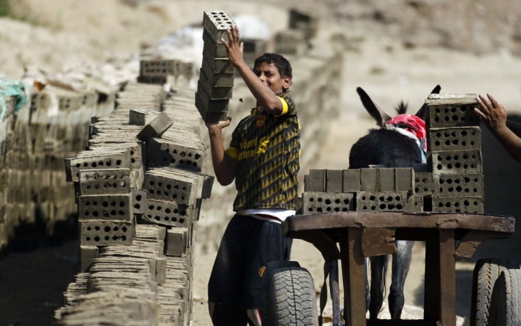 An Egyptian child loads a cart with cement bricks in a brick factory at the outskirts of Qalyobiya, 27 miles north of Cairo.