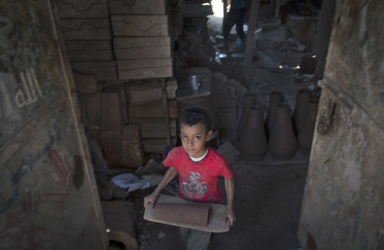 An Egyptian child carries a clay roof tile in a pottery workshop in old Cairo. Photo captured on Oct. 18.
