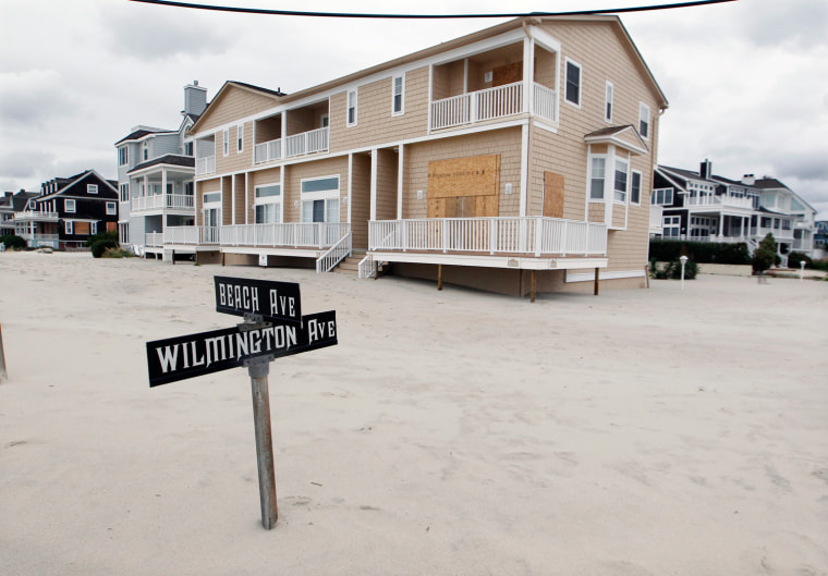 A street sign is partially buried in sand Tuesday morning, Oct. 30, in Cape May, N.J., after a storm surge from Sandy pushed the Atlantic Ocean over the beach and across Beach Avenue.
