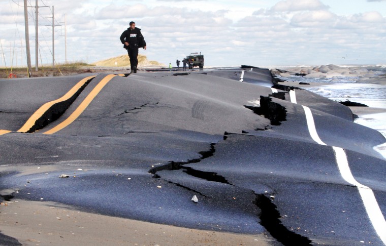Deputy Cliff Tice of the Dare County Sheriff's Department walks down damaged and impassable NC 12 leading into Mirlo Beach in Rodanthe, N.C. on Oct. 30.