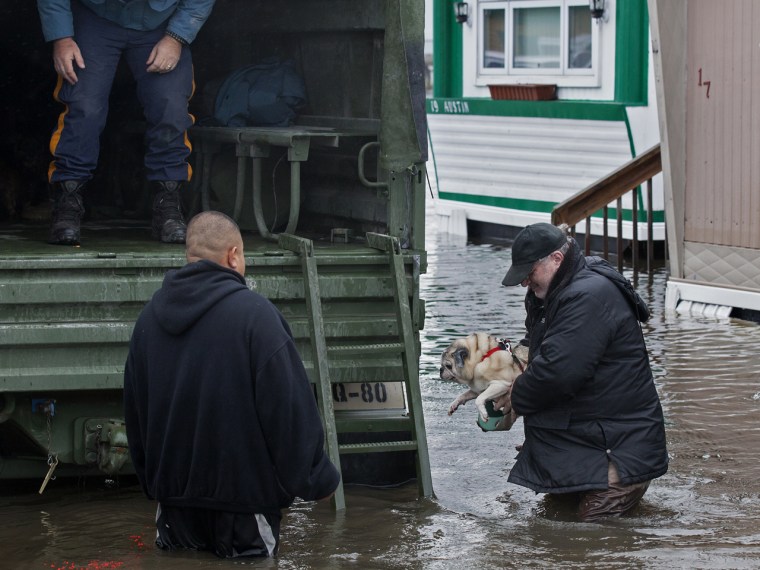 With the aid of New Jersey state police, a man walks with his dog to a National Guard vehicle after leaving his flooded home at the Metropolitan Trail...