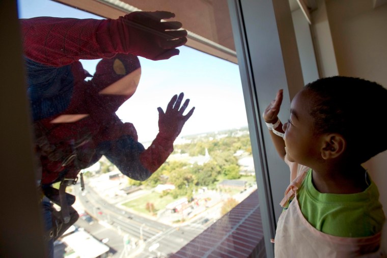 Dressed as Spiderman, a window washer with American National Skyline greets Le Bonheur Children's Hospital patient Orlando Farmer, 3, as he rappels do...