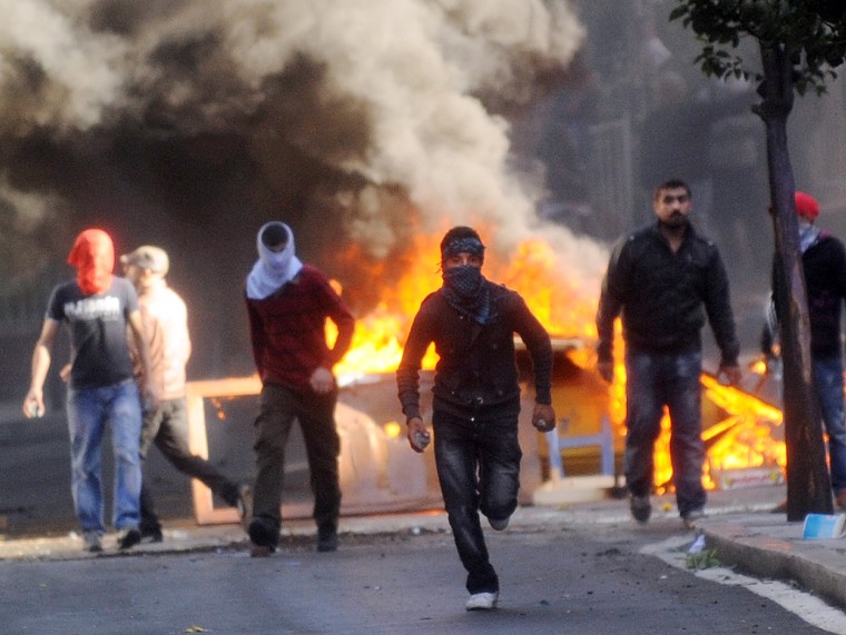Kurdish protestors stand in front of a flaming barricade during clashes between Kurdish demonstrators and riot police in Istanbul, Turkey, Oct. 30.
