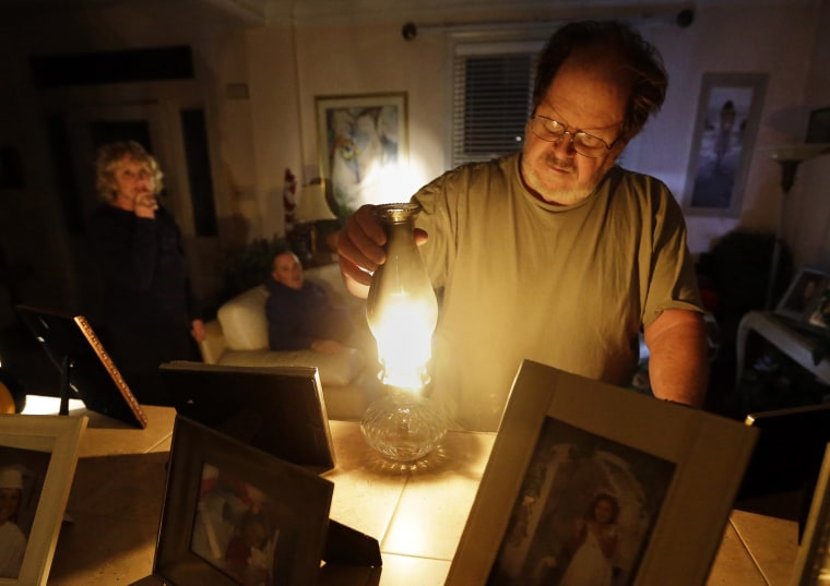 Jeff Willard lights a candle in his living room as his girlfriend, Diana Conte, back left, and her son, Ricky, wait for electricity to return in Ventnor City, N.J., Oct. 30, 2012. Sandy, the storm that made landfall Monday, cut power to more than 6 million homes and businesses.
