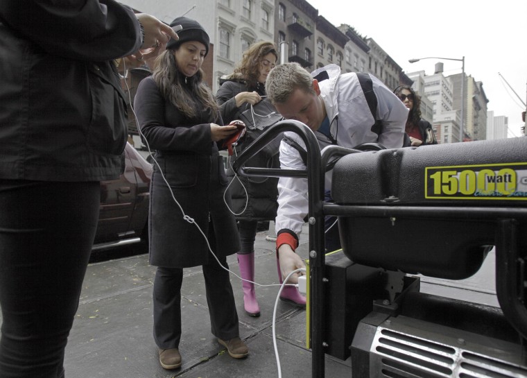 People in New York's Tribeca neighborhood wait for a chance to charge their mobile phones on an available generator setup on a sidewalk, Oct. 30. Sandy, the storm that made landfall Monday, caused cut power to more than 6 million homes and businesses.