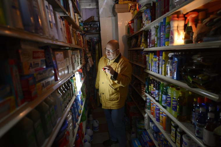 A man shops for groceries by flashlight at an East Village grocery store in New York, Oct. 30.