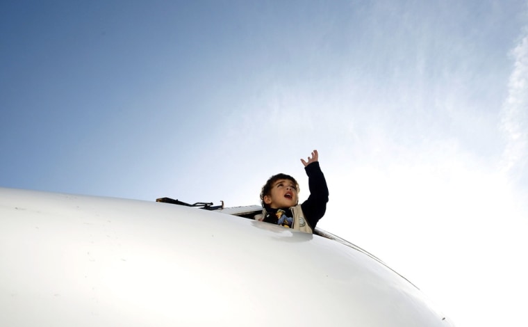 A child leans from the cockpit window of a plane at a kindergarten on October 31, 2012.