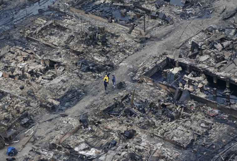Figures stand amid burned-out homes in the Breezy Point section of Queens, N.Y., on Oct. 30, 2012. The tiny beachfront neighborhood burned down as it was inundated by floodwaters from Sandy, transforming a quaint corner of the Rockaways into a smoke-filled debris field.