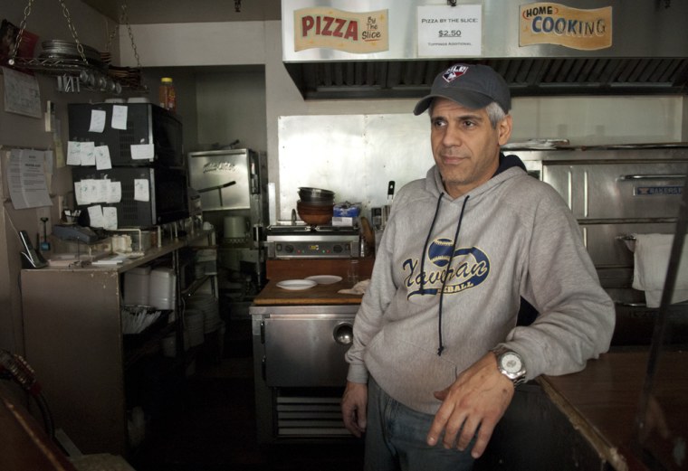 Vincent Sgarlato, owner of the 11B Express restaurant in the East Village, New York, stands behind the counter by the pizza ovens on Wednesday. His restaurant was closed for the day he gave away free pizza for several hours Tuesday.