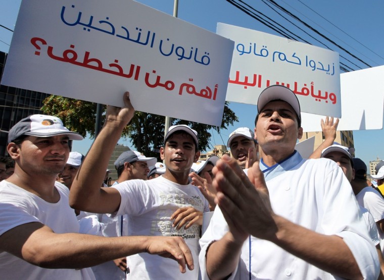Restaurants employees hold Arabic placards that read,
