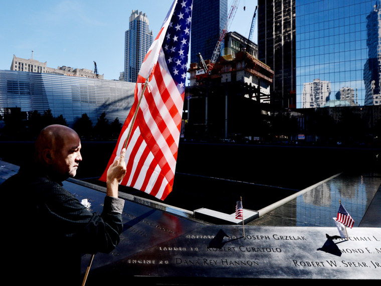 NEW YORK - SEPTEMBER 11: Marshall Rodriguez of New York holds an American flag at the edge of the South Pool while visiting the names of friends he lost during memorial ceremonies for the eleventh anniversary of the terrorist attacks on lower Manhattan at the World Trade Center site September 11, 2012 in New York City. New York City and the nation are commemorating the eleventh anniversary of the September 11, 2001 attacks which resulted in the deaths of nearly 3,000 people after two hijacked planes crashed into the World Trade Center, one into the Pentagon in Arlington, Virginia and one crash landed in Shanksville, Pennsylvania.