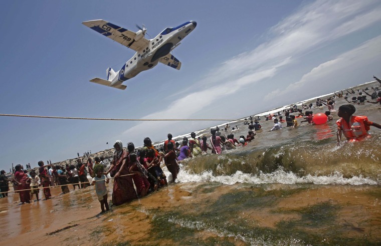 Demonstrators hold on to ropes as a plane flies over.