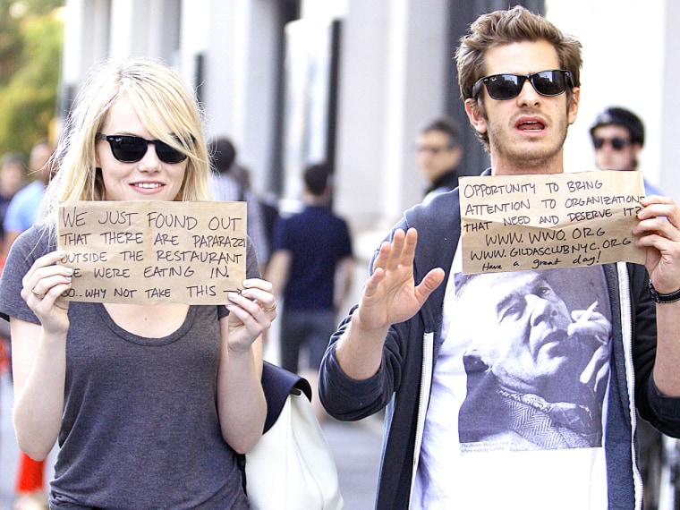 Actress Emma Stone and boyfriend actor Andrew Garfield used the paparazzi to their advantage by holding up cardboard signs to promote some charitable organizations.