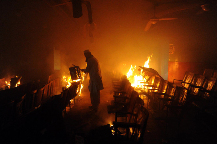 A Pakistani Muslim demonstrator carries material inside a burning cinema during a protest against an anti-Islam film in Peshawar on Sept. 21.