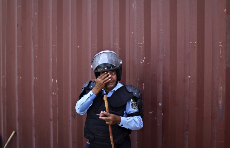 A Pakistani riot police officer reacts to tear gas fired by other officers during clashes with protestors after they tried to approach the U.S. embassy, in Islamabad, Pakistan, on Sept. 21. Pakistani police opened fire on rioters who were torching a cinema during a protest against an anti-Islam film Friday, and security forces clashed with demonstrators in several other cities in Pakistan on a holiday declared by the government so people could rally against the video. Thousands of people protested in several other countries, some of them burning American flags and effigies of President Barack Obama.