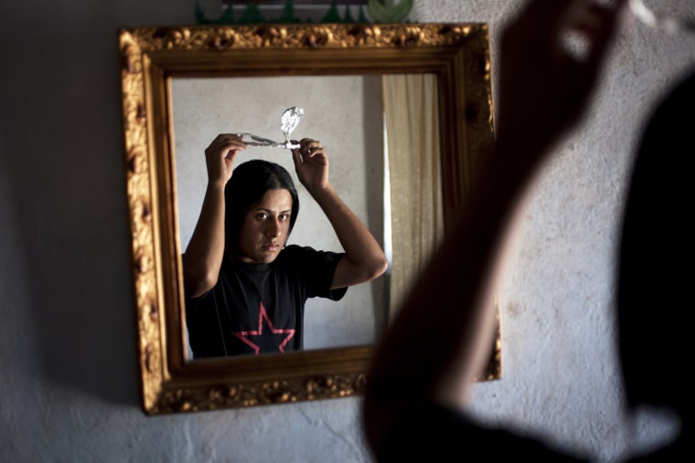 Linda Elizabeth Tylor Martinez, 22, looks in the mirror as she tries on the paper crown that she will use to compete in the upcoming the Miss Night Queen beauty contest in the El Milagro neighborhood of Guatemala City, June 15, 2012. Born a man, Tylor is a transgender woman who moves between two distinct worlds: one male, one female.