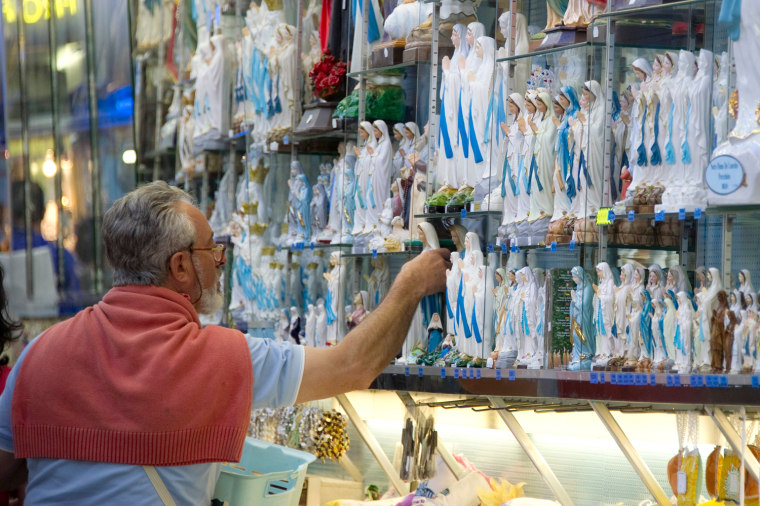 A Catholic pilgrim looks at Virgin Mary statues in a gift shop during the Feast of the Assumption on Aug. 15, 2011 in the Sanctuary of Our Lady in the French pilgrimage city of Lourdes.