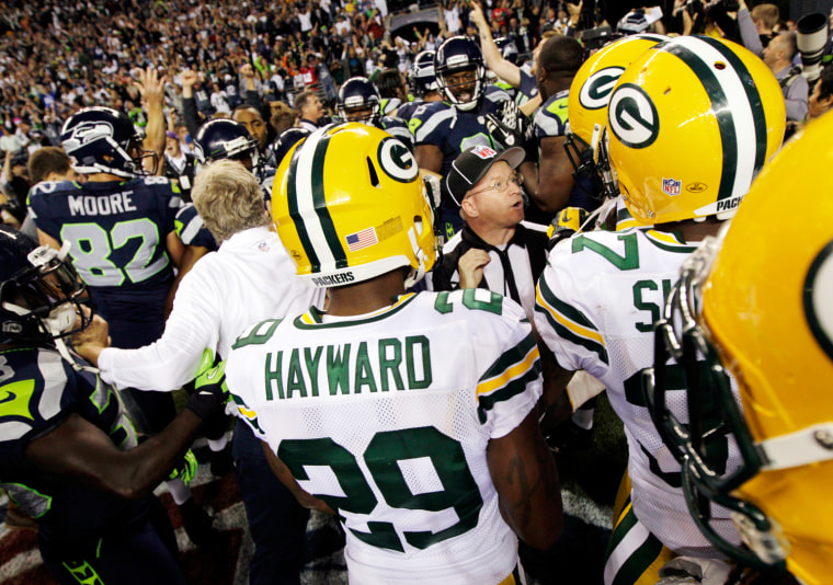 Officials try to sort out the final play of an NFL football game between the Green Bay Packers and the Seattle Seahawks as players and coaches swarm the field on Monday night.