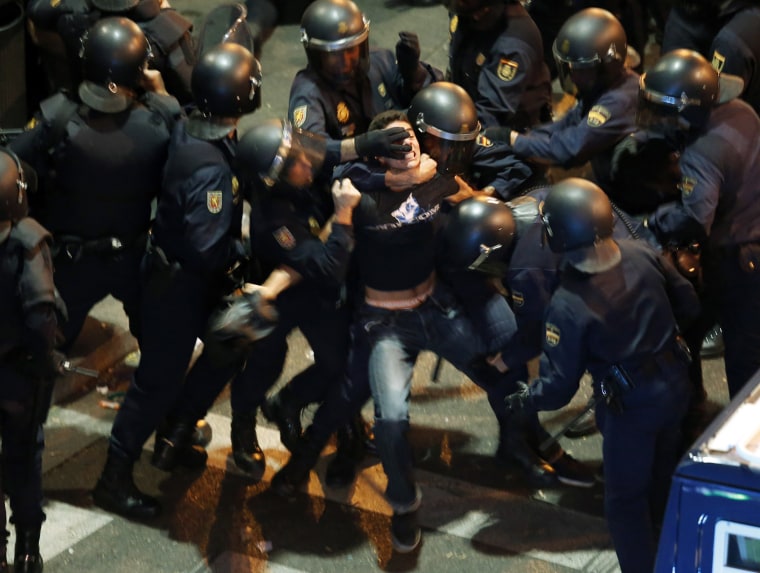 A demonstrator struggles with Spanish National Police riot officers outside the Spanish parliament in Madrid, Sept. 25, 2012.