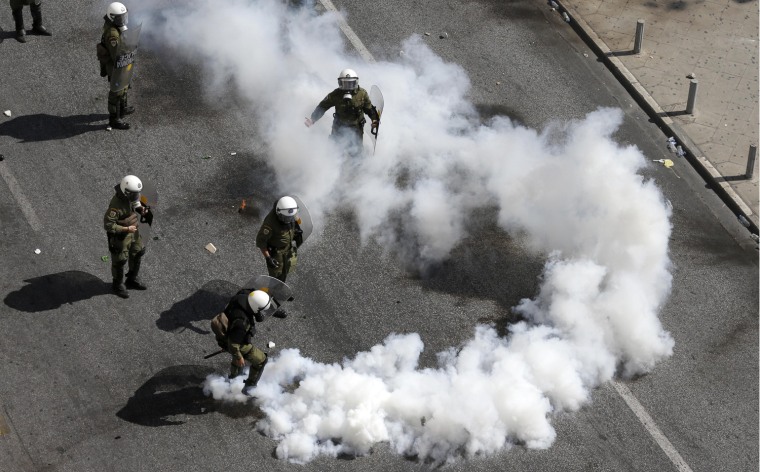 A riot police officer kicks a tear gas canister during clashes in Athens on Sept. 26. Police clashed with protesters hurling petrol bombs and bottles after an anti-government rally called as part of a general strike in Greece turned violent. About 50,000 people joined the union-organized march held during a general strike against new austerity measures planned in the crisis-hit country.