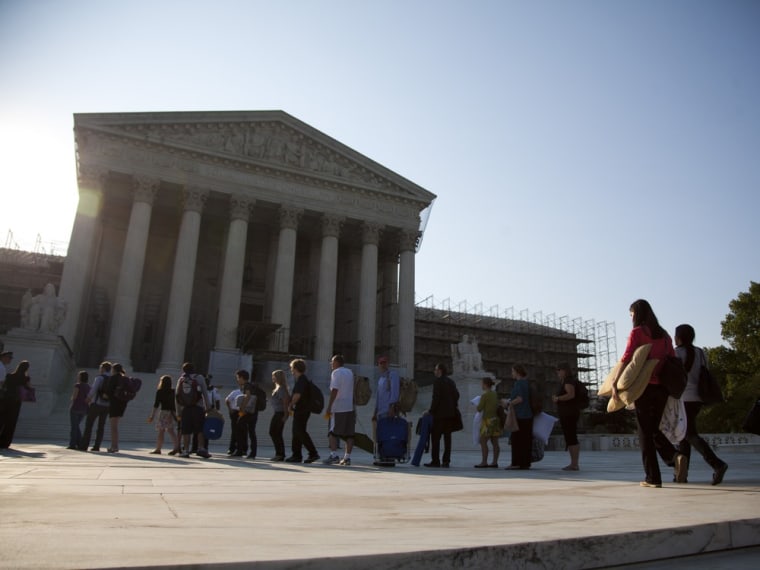 People who waited in line overnight to hear the Supreme Court on a landmark case on health care hold their belongings as they make their way into the court in Washington, Thursday, June 28, 2012.