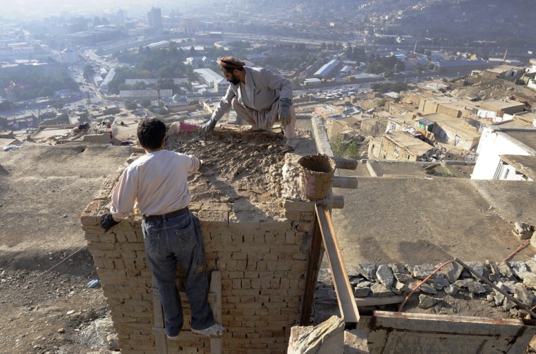 Saber, a resident of the hillside neighborhood of Jamal Mina applies a layer of concrete to a room he was adding to his home high above downtown Kabul on Sept. 27.