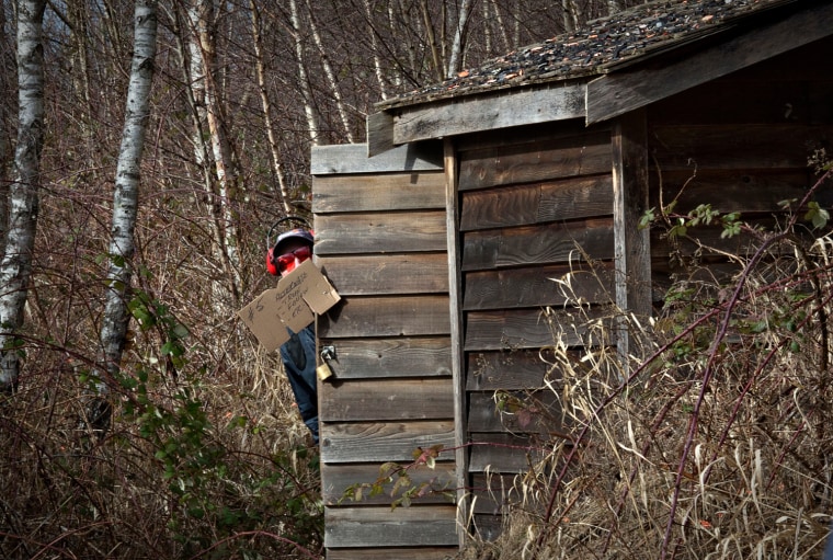 A Vancouver Gun Club member peeks out from behind the hut where sporting clays are fired.