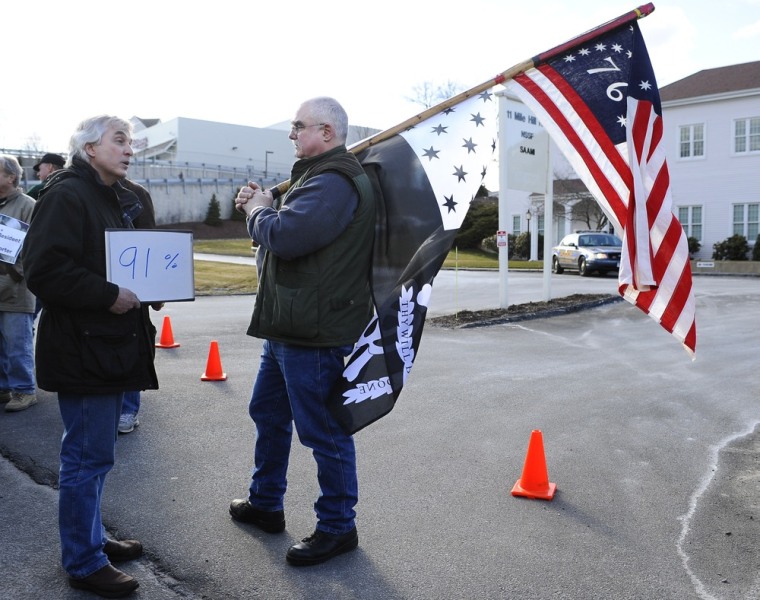 John Woodall. left, of Newtown, Conn., carries a sign that he says indicates the percentage of Americans who support universal background checks, speaks with Gordon Jones of Southbury, Conn., a supporter of gun rights during a rally outside the National Shooting Sports Foundation headquarters in Newtown on March 28.