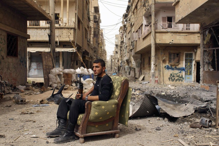 A member of the Free Syrian Army holds his weapon as he sits on a sofa in the middle of a street in Deir al-Zor on April 2.