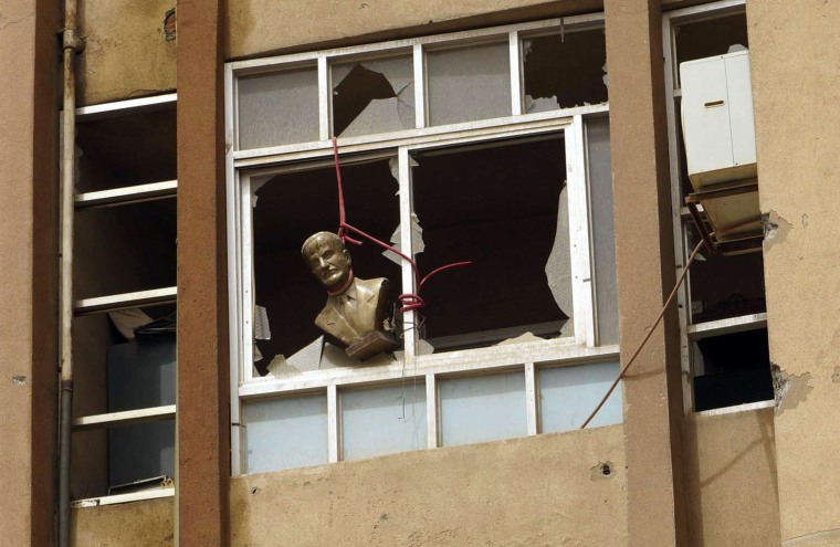 A bust of late Syrian President Hafez al-Assad, father of the current president Bashar al-Assad, is seen hung at a broken window of a building in Deir al-Zor on April 2.
