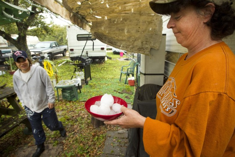 Jeanne Malone, left, walks past Christine Hubbard as she holds a bowl full of hail stones she collected following a hail storm Wednesday, April 3, 2013, in Hitchcock, Texas. Thousands of people in the Houston and Galveston areas have lost electricity in overnight storms that dropped hail the size of baseballs and broke windows. Emergency officials say no injuries were reported.