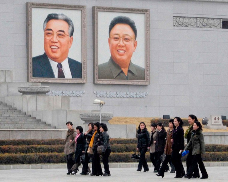 Women walk past portraits of North Korea's founder Kim Il Sung and late leader Kim Jong Il in Pyongyang on Monday.