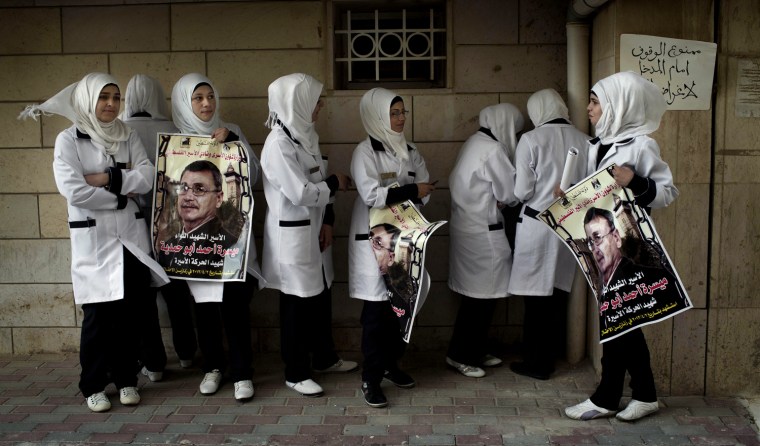 Palestinian nurses hold posters with the picture of Maysara Abu Hamdiyeh with Arabic that reads,