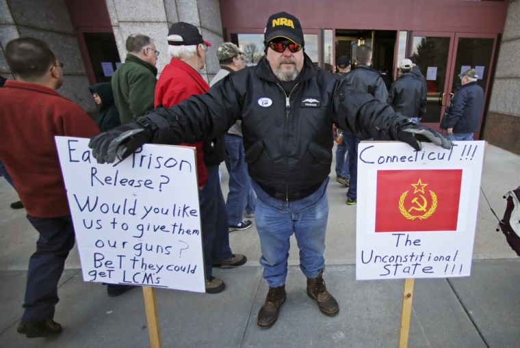 Paul Regish of East Hartford, Conn., holds signs as gun rights advocates enter the legislative office building at the Capitol in Hartford, Conn., on April 3.