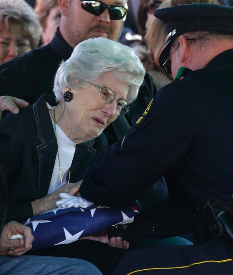 Wyvonne McLelland, mother of Kaufman County District Attorney Mike McLelland receives a flag from Nathan Foreman, during the grave side funeral services for the couple in Wortham, Texas, April 5.