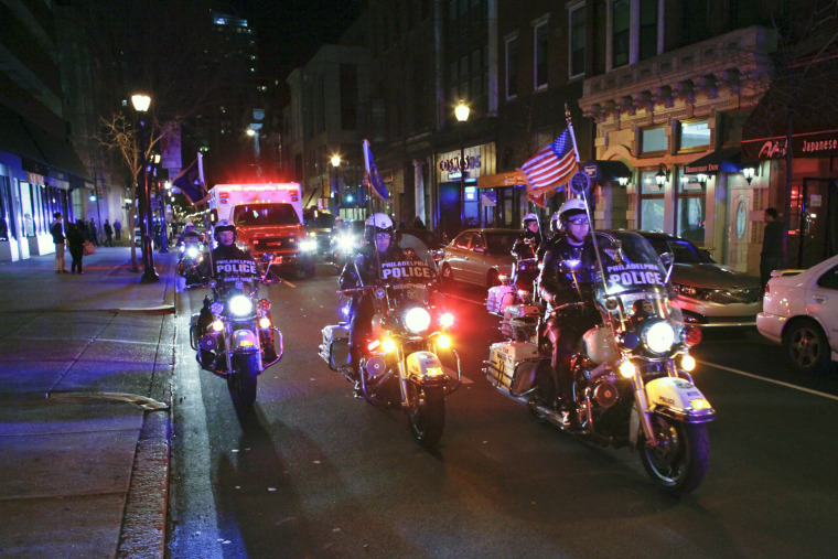 Police escort an ambulance carrying the body of fallen firefighter Capt. Michael Goodwin from Thomas Jefferson Hospital.