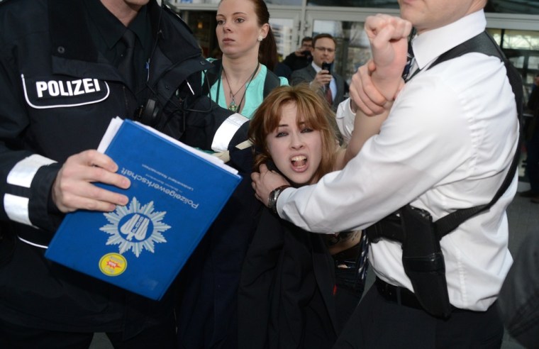 A demonstrator is held by security staff.