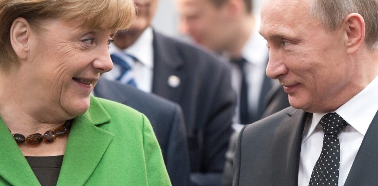 German Chancellor Angela Merkel and Russian President Vladimir Putin exchange glances after the incident involving topless demonstrators.