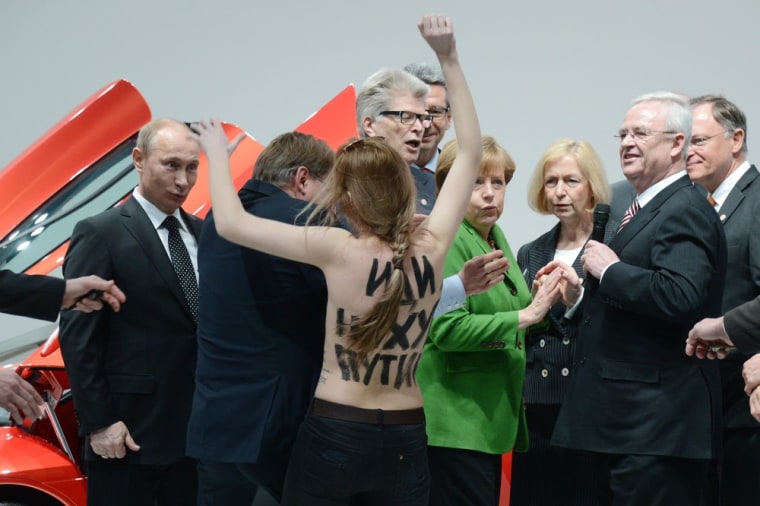 An eye-opening experience for Russian President Vladimir Putin (left) as he is confronted by a topless demonstrator during a tour of the Hanover Fair in Hanover, Germany, on April 8, 2013. He was accompanied by German Chancellor Angela Merkel (center right) and Volkswagen Chief Executive Officer Martin Winterkorn (extreme right).
