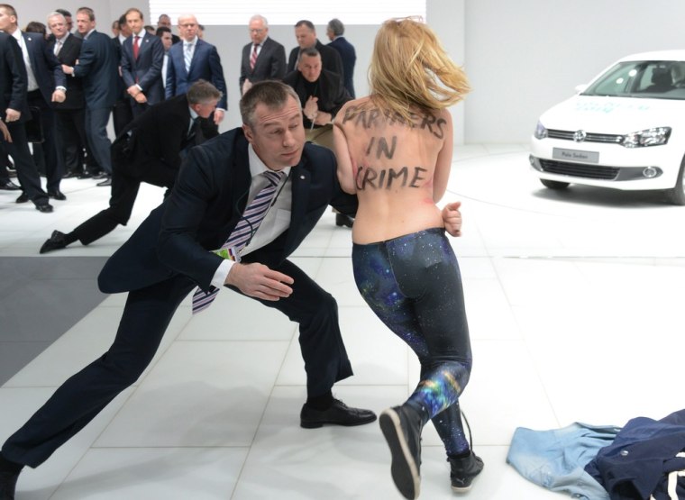 Security staff stop another topless demonstrator at the Volkswagen stand at the Hanover Fair.