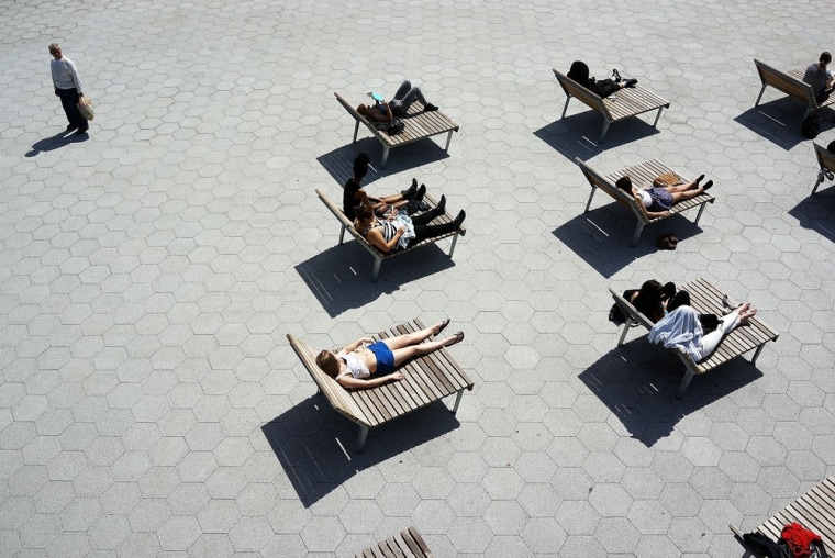 People relax along the East River in lower Manhattan during warm weather on April 9 in New York City. For the first time since October, temperatures are expected to rise above 70 degrees this week in New York and surrounding areas.