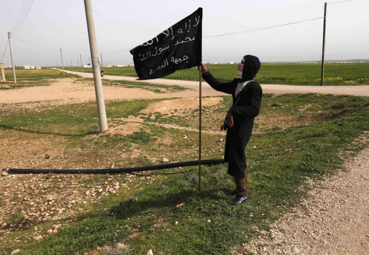 A fighter from the Syrian rebel group Jabhat al-Nusra holds an Islamist flag in Raqqa province, eastern Syria, in this March 12, 2013 photo. The Iraqi wing of al-Qaeda announced on Tuesday that Nusra was now its Syrian branch and the two groups would operate under one name -- the Islamic State in Iraq. The flag reads