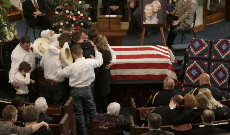 The family of Kaufman County District Attorney Mike McLelland and his wife, Cynthia, comfort each other during their funeral services in Wortham, Texas, on April 5.