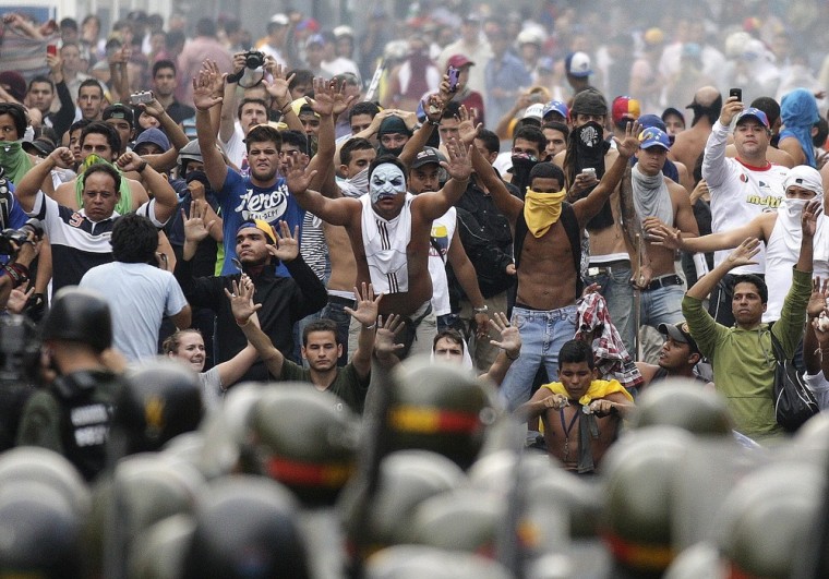 Supporters of opposition leader Henrique Capriles face off against riot police as they demonstrate for a recount of the votes in Sunday's election, in Caracas, Venezuela, on April 15, 2013.