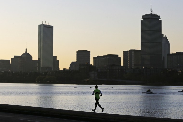 A solitary runner heads down the banks of the Charles River in Cambridge, Mass., on Tuesday with the Boston skyline in the background, one day after explosions killed three and injured at least 176 at the Boston Marathon.
