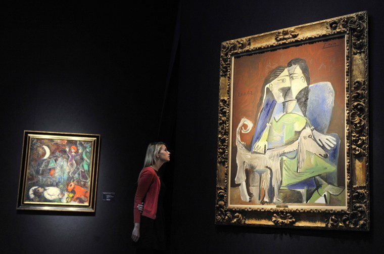 A staff member at Christie's auction house staff looks over Pablo Picasso's painting \"Femme au chien.\"