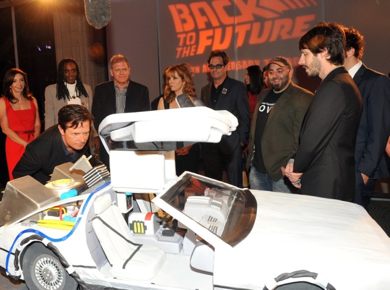 Michael J. Fox checks out an DeLorean created by the \"Ace of Cakes\" crew for the \"Back to the Future\" reunion, as Geoff, right, and Duff, second from right, from the show look on.