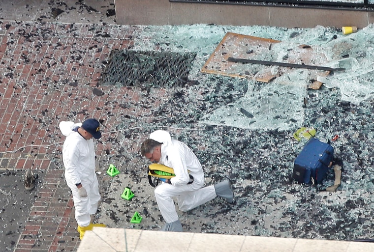 Two men in hazardous materials suits put numbers on the shattered glass and debris as they investigate the scene at the first bombing on Boylston Street in Boston on April 16, 2013 near the finish line of the 2013 Boston Marathon.