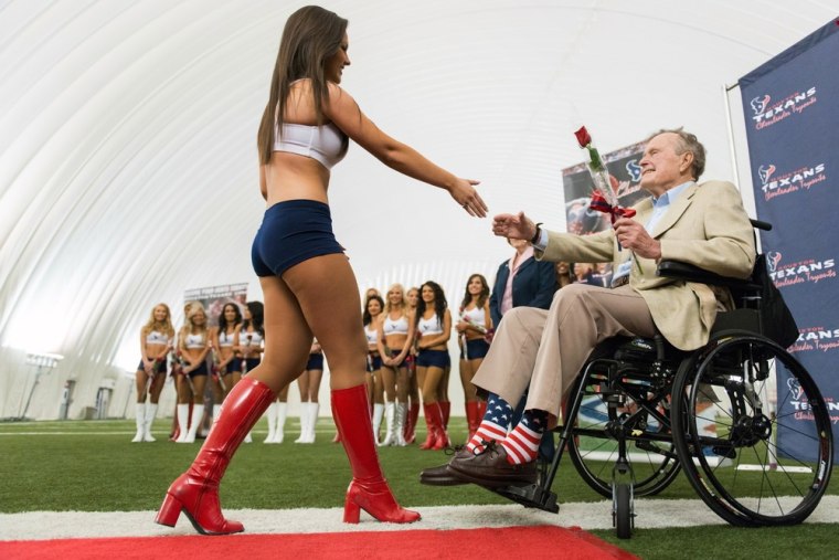 George H.W. Bush presents a rose to a new Texans cheerleader.